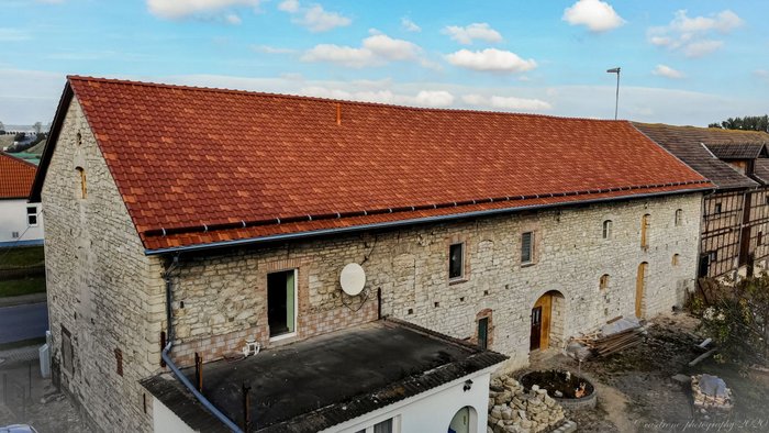 Abbildung 8: Aktuelle Drohnenaufnahme des Pferdestalls, den Julius Grote und seiner Frau Thekla errichten ließen. Blick nach Nordost. Links ist im oberen Bereich des Westgiebels das vorläufig gesicherte Giebelfenster zu erkennen. Darüber befand sich die Inschriftentafel von 1856. © casdrone-photography, Jannis Wendt.